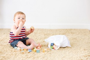 Baby playing with blocks on clean carpet.